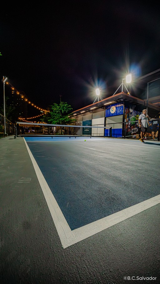 Night pickleball court with a ball on the line